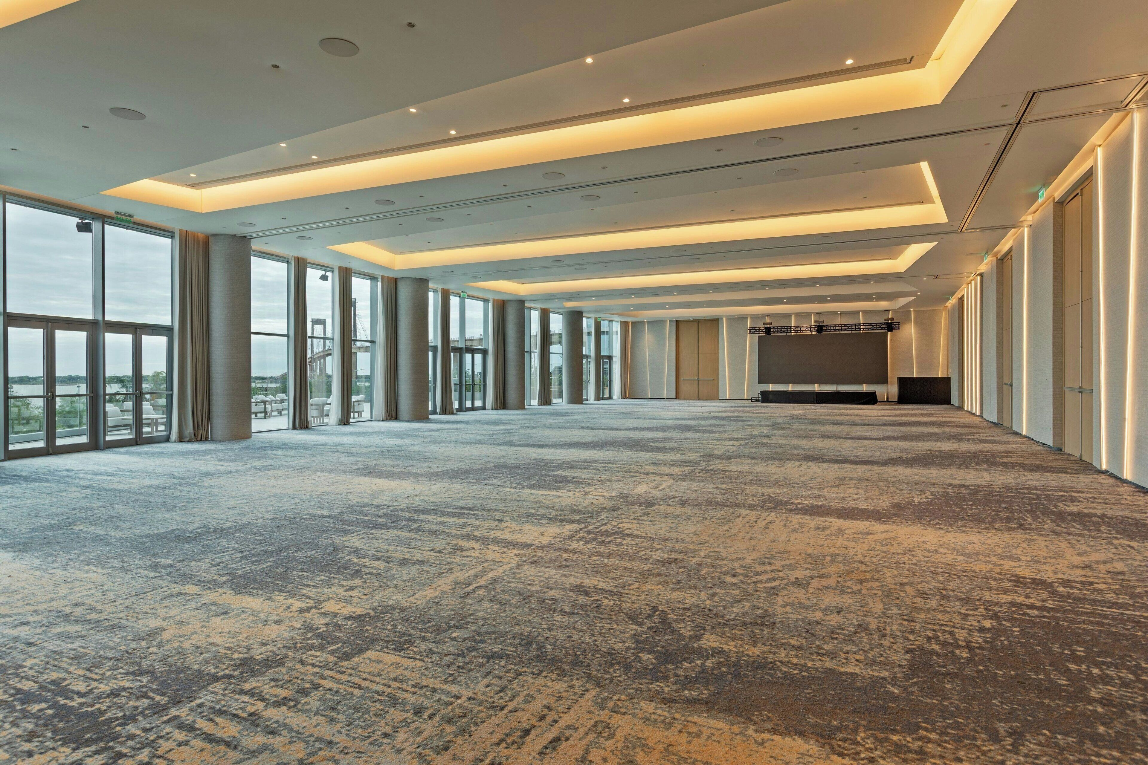 Una sala de conferencias amplia y bien iluminada, con ventanas grandes, piso alfombrado y una larga mesa.