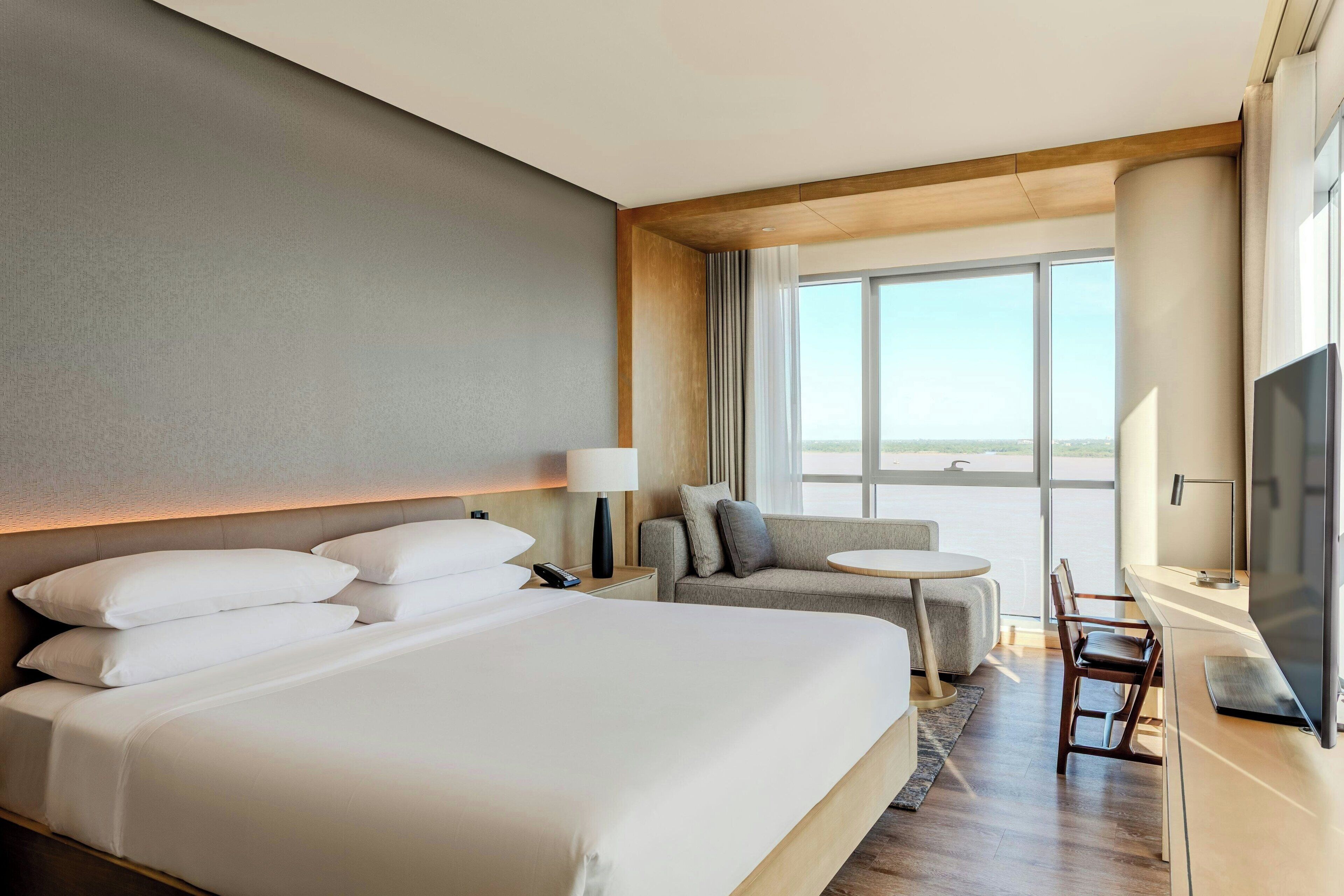 A hotel room with a large bed, a sofa, a small table, and a TV.
