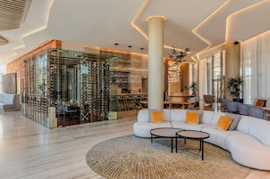Un interior moderno con un botellero de vidrio, un área de estar con sofá y mesa de centro, y una barra con taburetes.