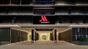 A modern hotel entrance with a prominent logo, a glass facade, and a well-lit pathway leading to the entrance. - Marriott Corrientes Hotel (Corrientes)