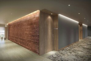 A modern hallway with a brick-patterned wall, a wooden door, and a carpeted floor.