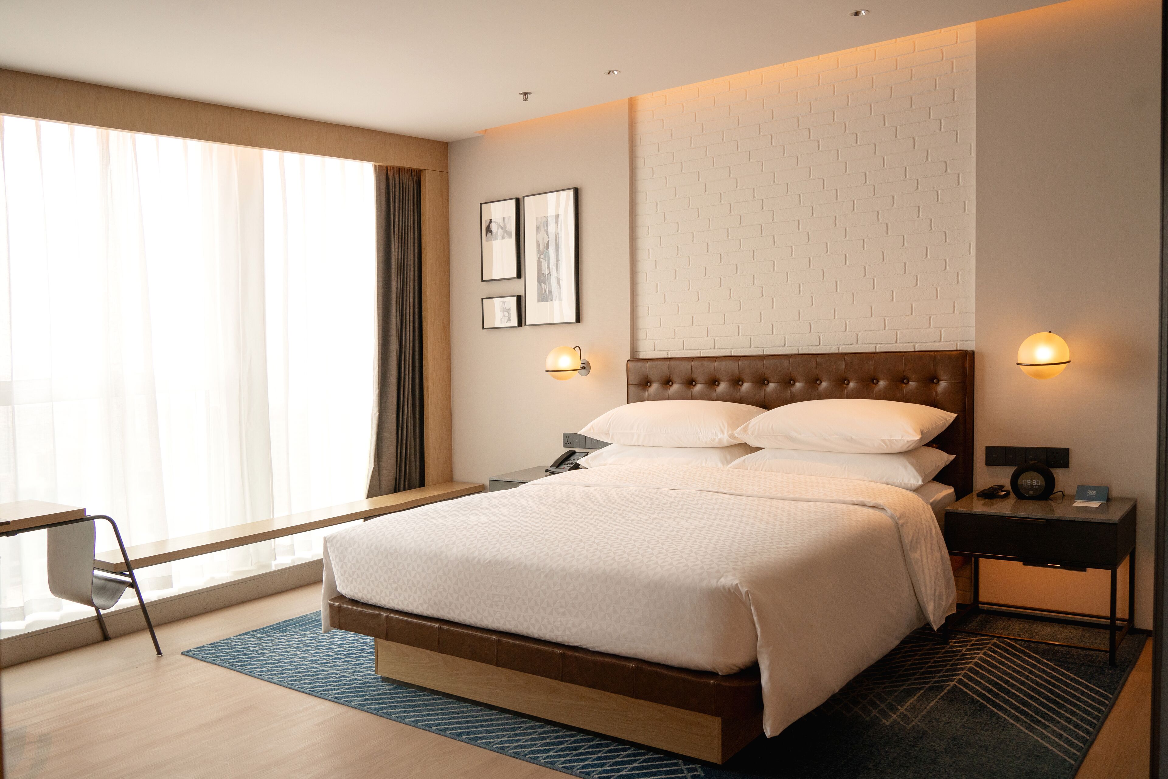 Une chambre d’hôtel moderne dotée d’un grand lit, d’un bureau et offrant une vue sur l’extérieur.