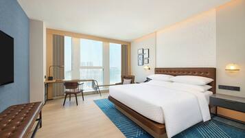 Een moderne hotelkamer met een groot bed, een bureau en uitzicht op de stad.
