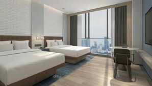 Une chambre d’hôtel avec deux lits, un bureau et une grande fenêtre donnant sur la ville.
