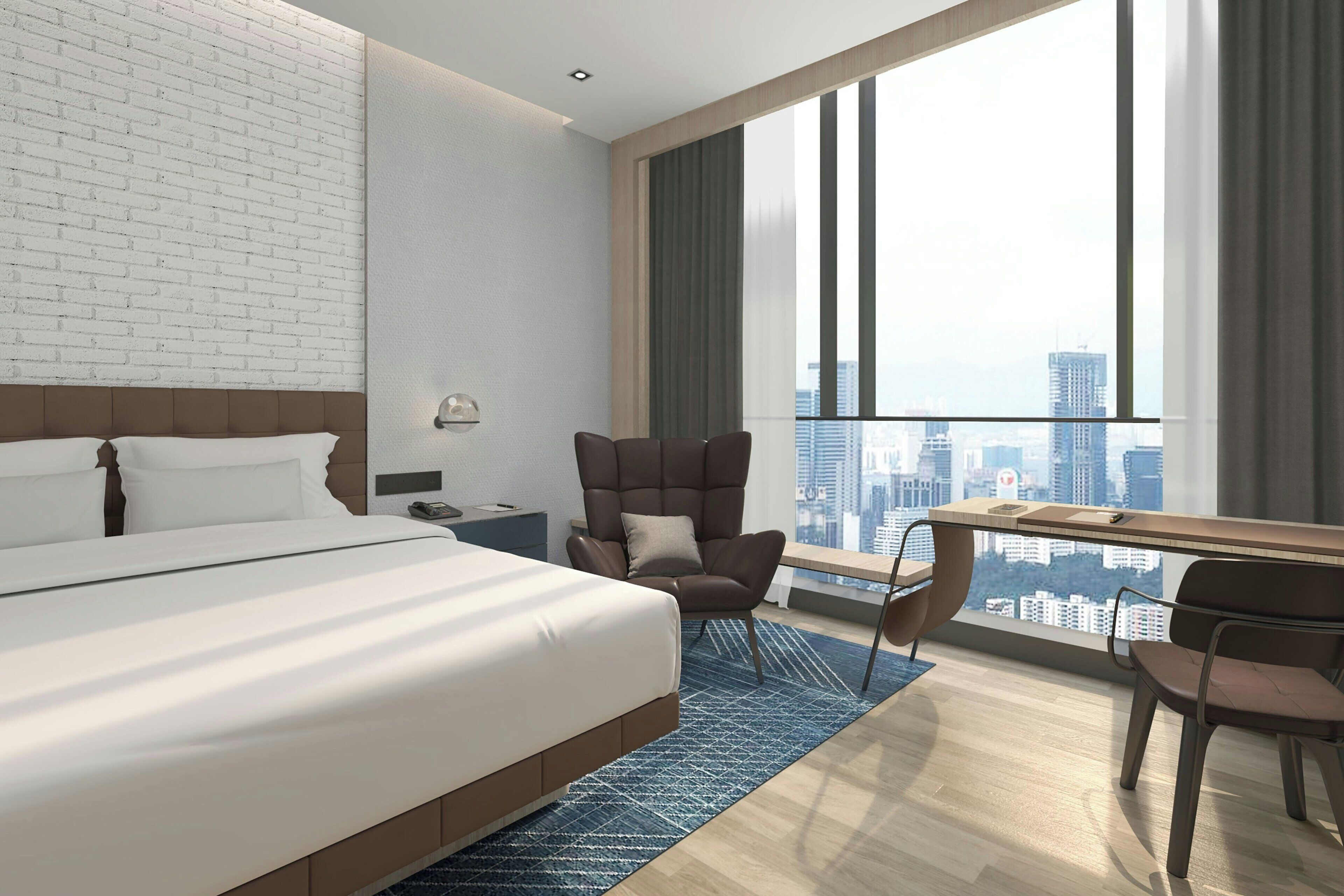 A modern hotel room with a large bed, a desk, a chair, and a view of the cityscape through large windows.