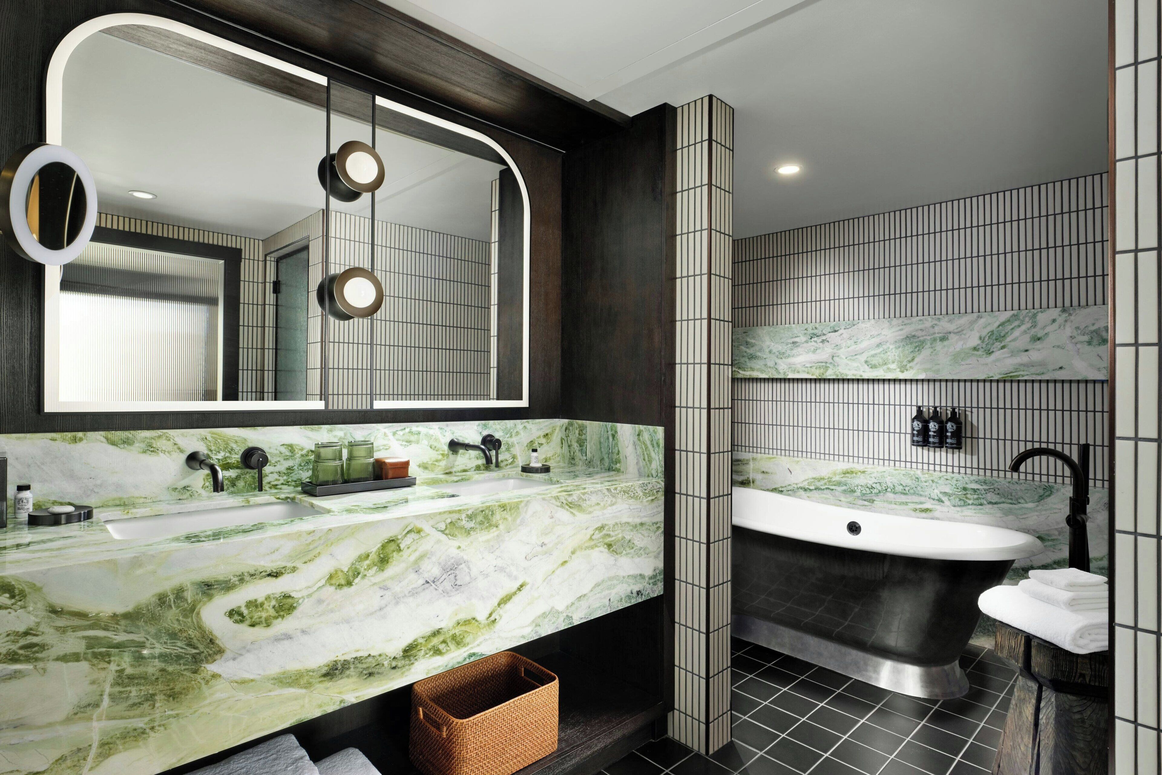Ein modernes Badezimmer mit großem Spiegel, zwei Waschbecken, einer Badewanne und einer Marmorarbeitsplatte.