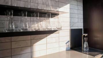 A kitchen with a marble backsplash, a stainless steel countertop, and a water dispenser.