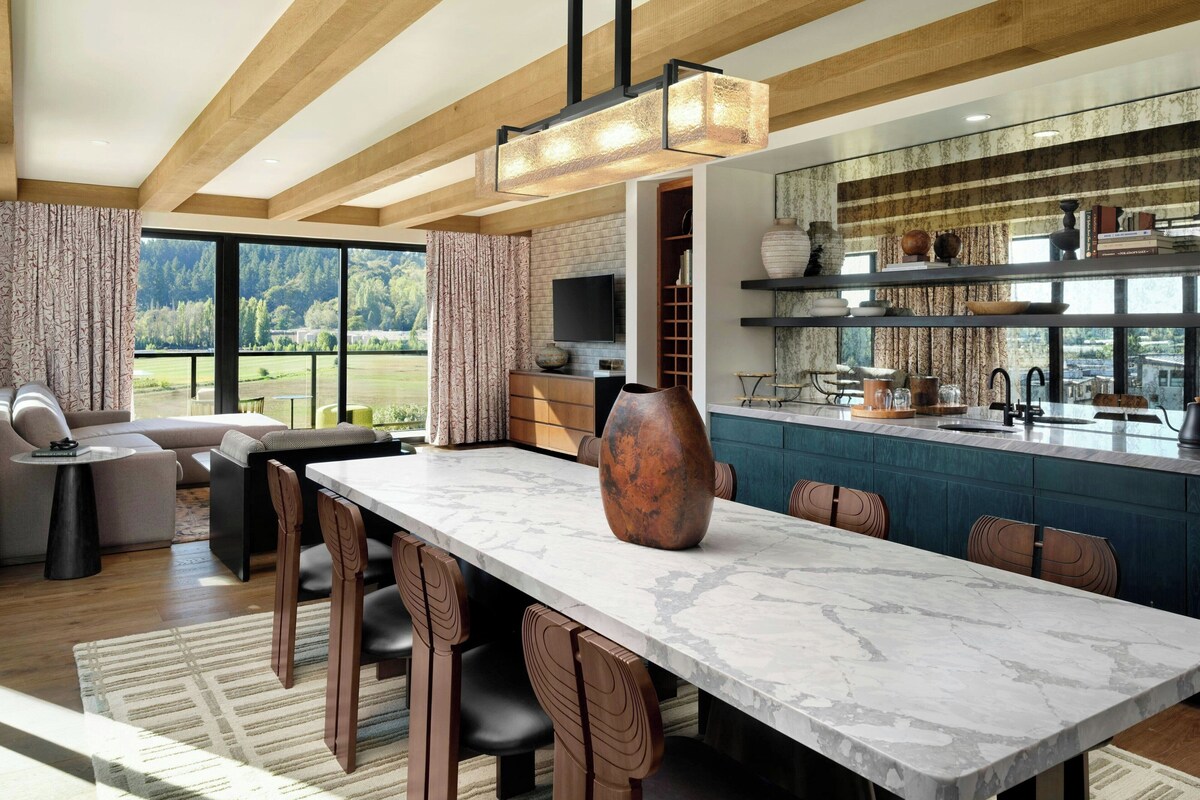 Una cocina moderna con encimera de mármol, un jarrón grande y un comedor con sillas y una mesa.