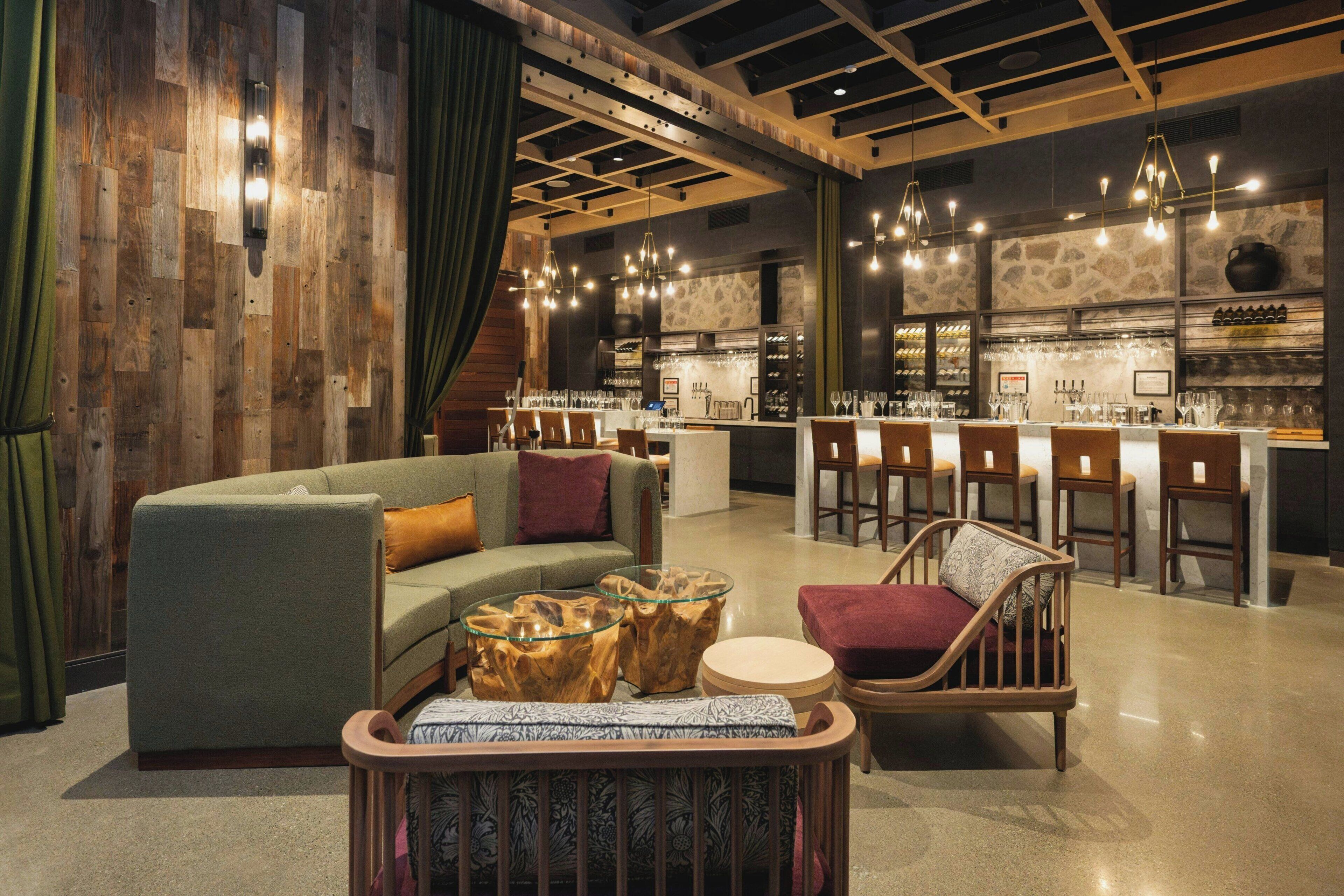 A modern bar area with a wooden ceiling, bar stools, and a counter with a wine rack.