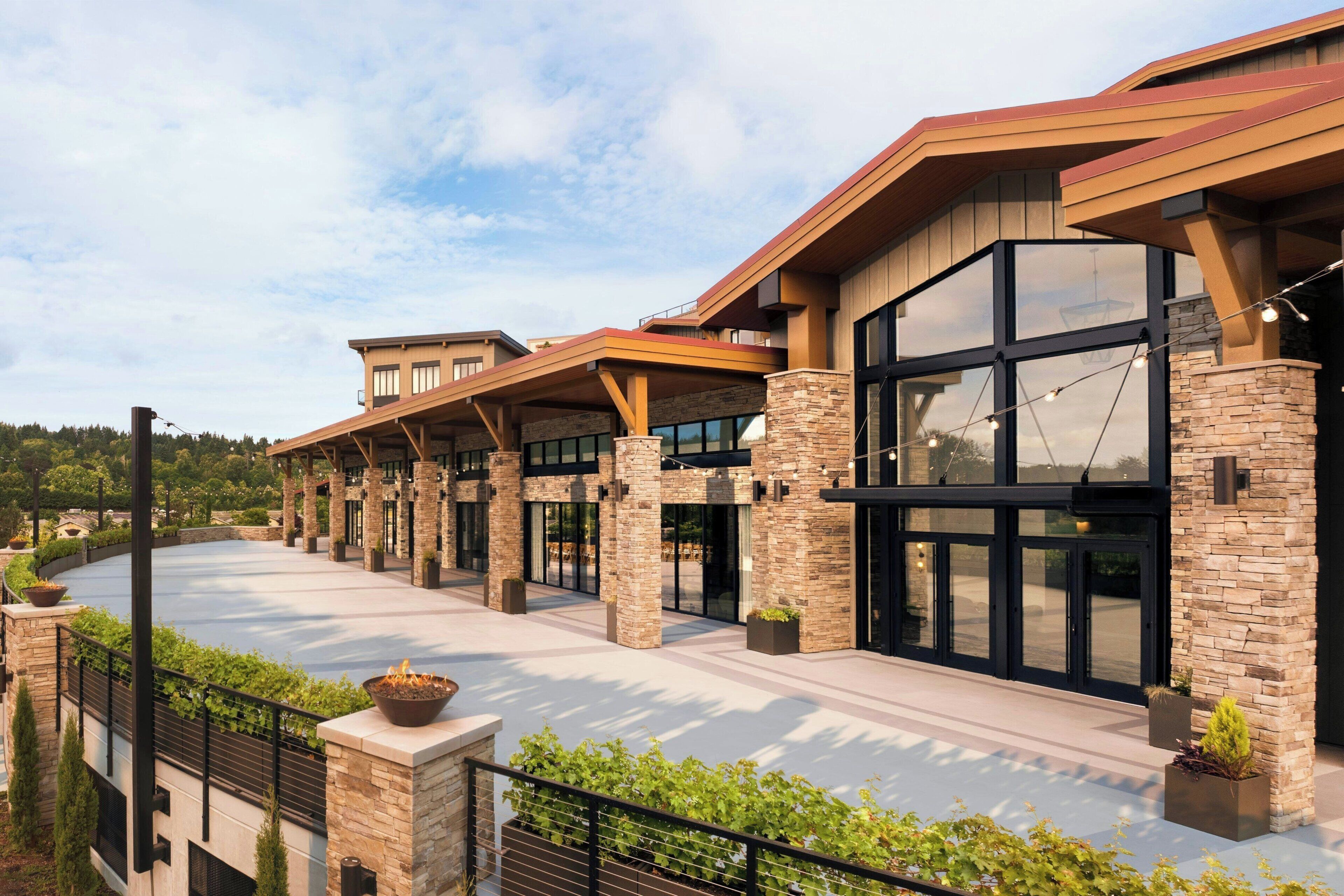 A modern hotel with a covered outdoor area, stone pillars, and large windows.