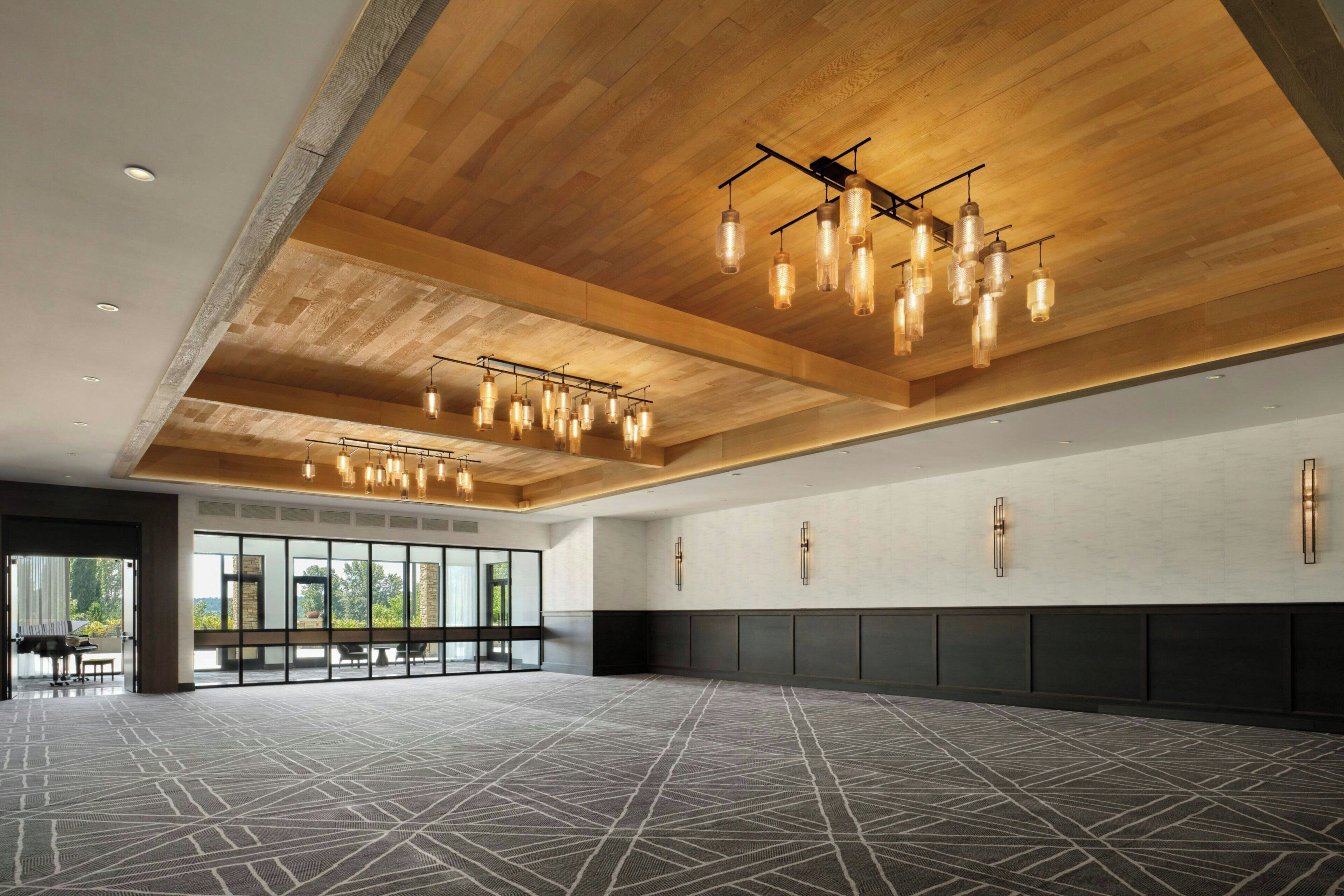 A spacious hall with a high ceiling, multiple hanging light fixtures, and a patterned carpet.