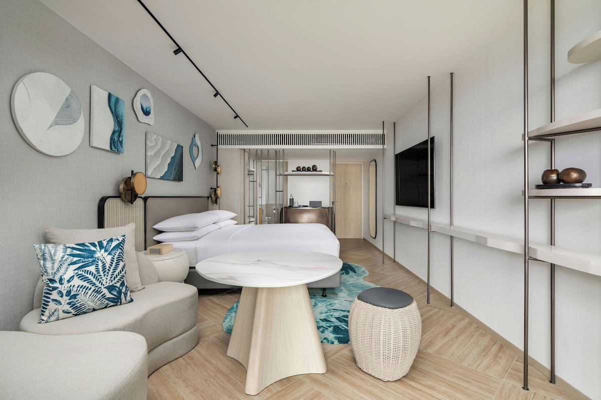 Ein modernes Hotelzimmer mit einem Bett, einem runden Tisch, einer Couch und Kunstwerken an den Wänden.