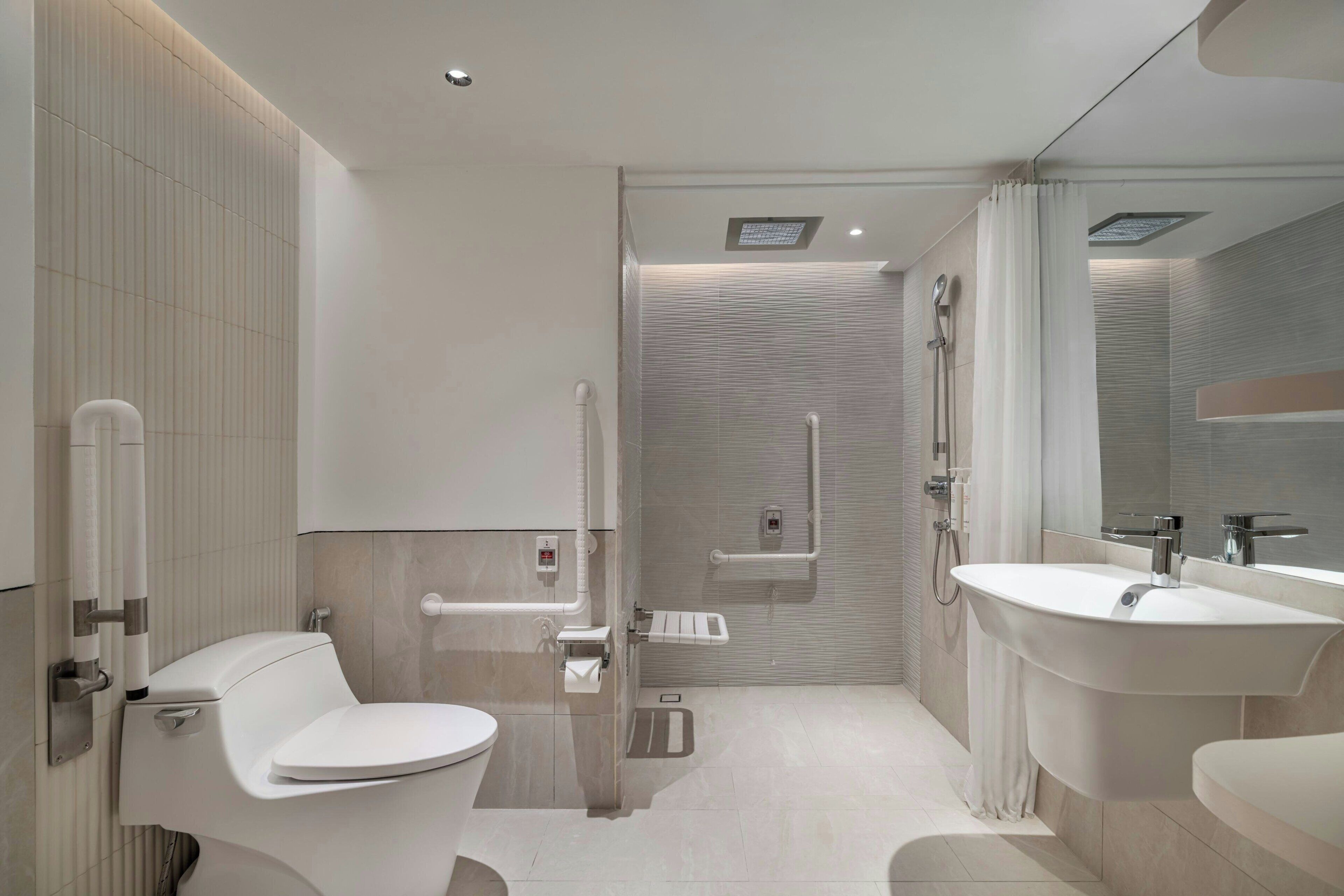 A modern bathroom with a toilet, bidet, shower, and a large sink.