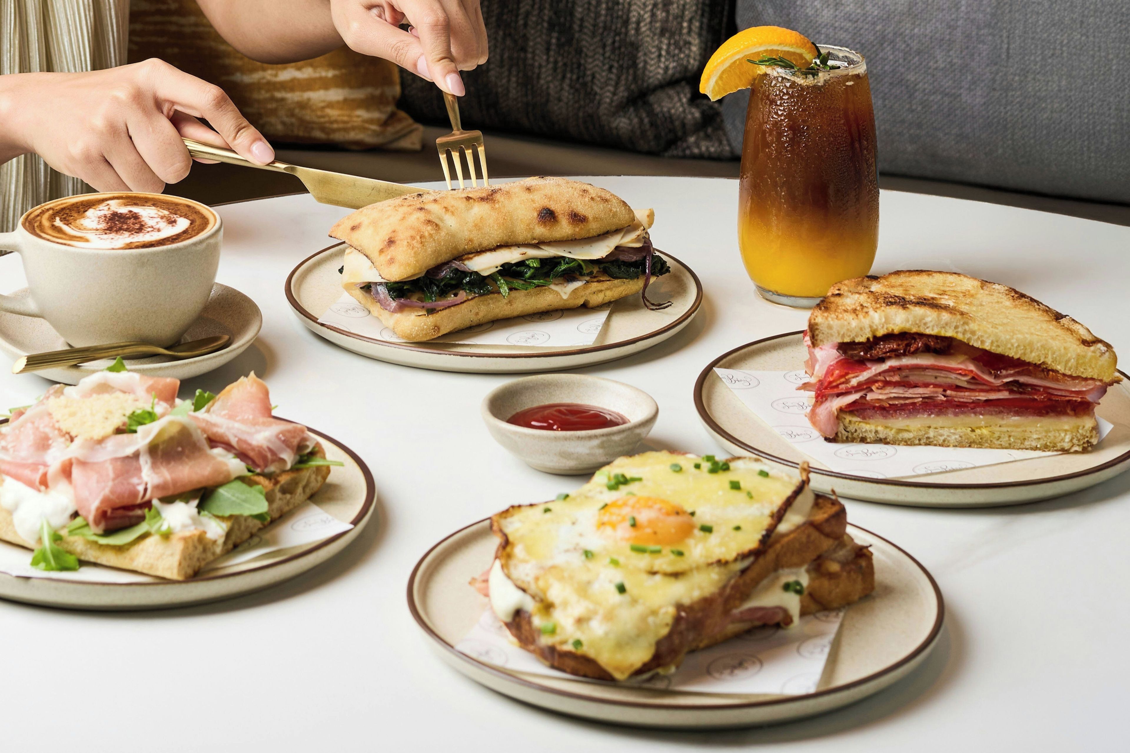 A variety of food items on plates, including sandwiches and a cup of coffee.