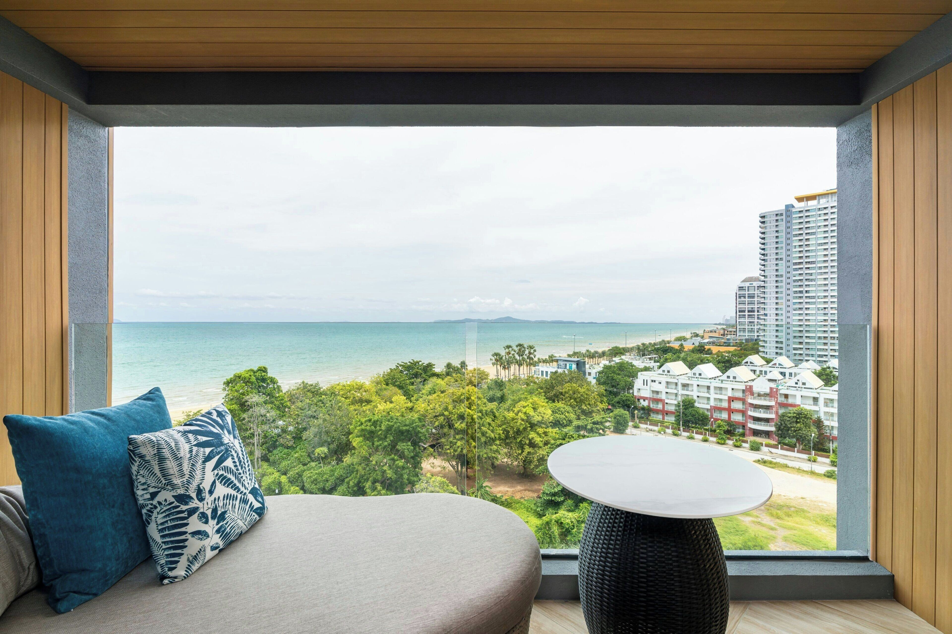 A room with a large window overlooking a beach and buildings.