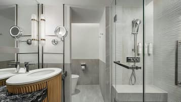 Un baño moderno con tocador, dos lavamanos, inodoro y zona de ducha con mampara de vidrio.