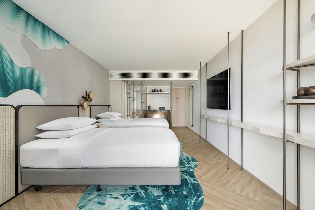 Ein modernes Hotelzimmer mit einem großen Bett, einem Schreibtisch, einem Spiegel und einem Fernseher.
