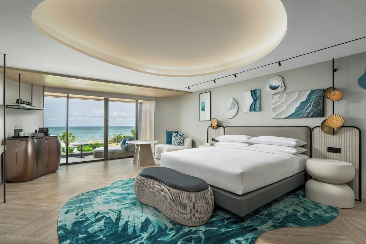 Ein modernes Schlafzimmer mit einem großen Bett, Meerblick und einem Balkon.