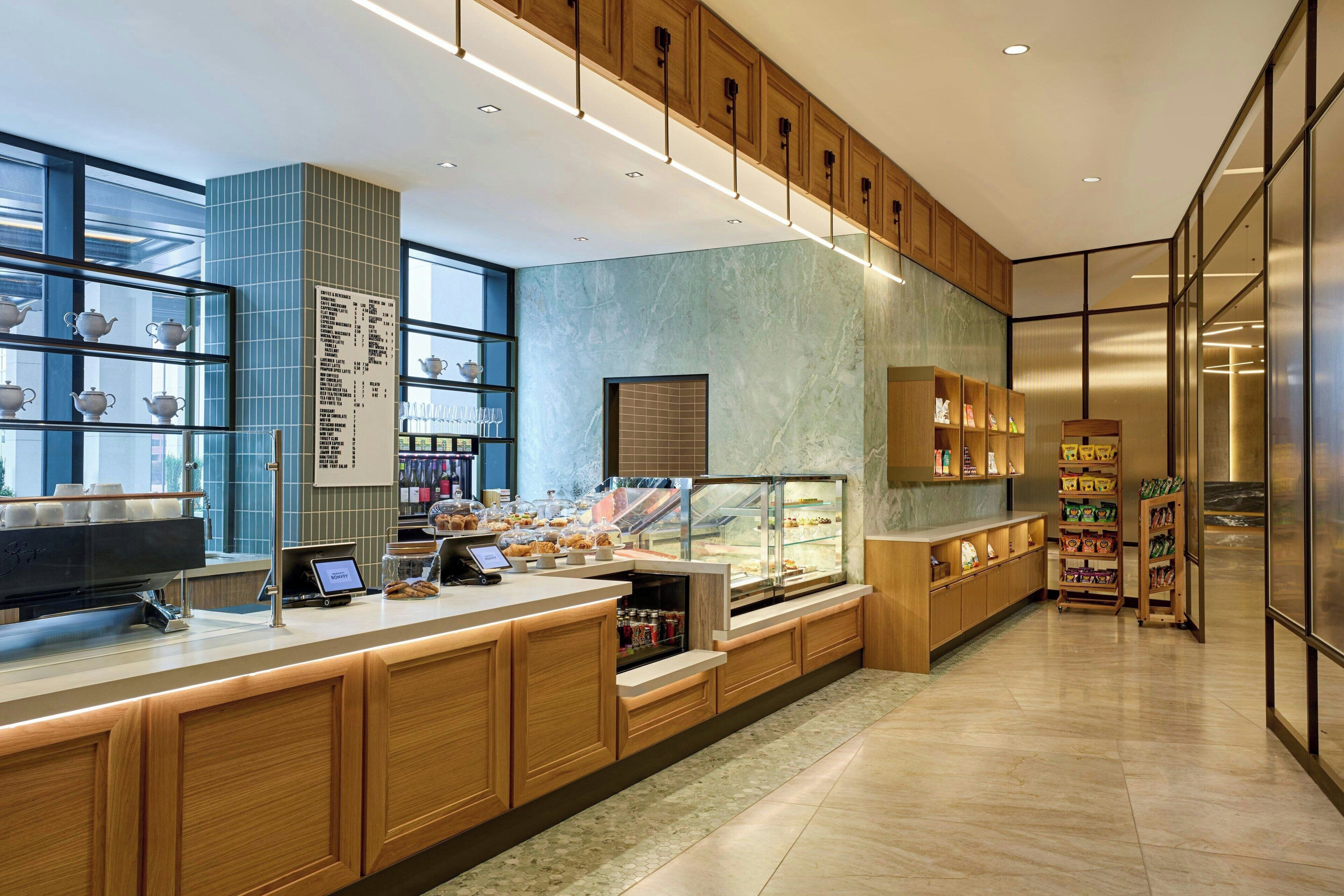 A modern cafe interior with a long counter, display cases, and a menu board.