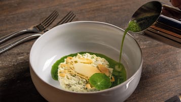 A bowl of soup with a spoon pouring green liquid into it.