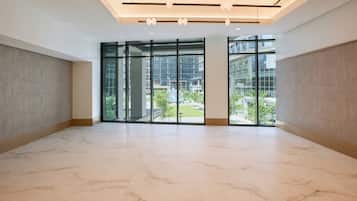 A spacious room with a large glass door leading to an outdoor area, featuring a marble floor and modern lighting fixtures.