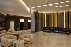 A modern lobby with a reception desk, seating area, and contemporary lighting fixtures.