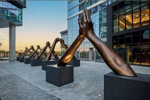A series of bronze hand sculptures in a plaza with modern buildings in the background.