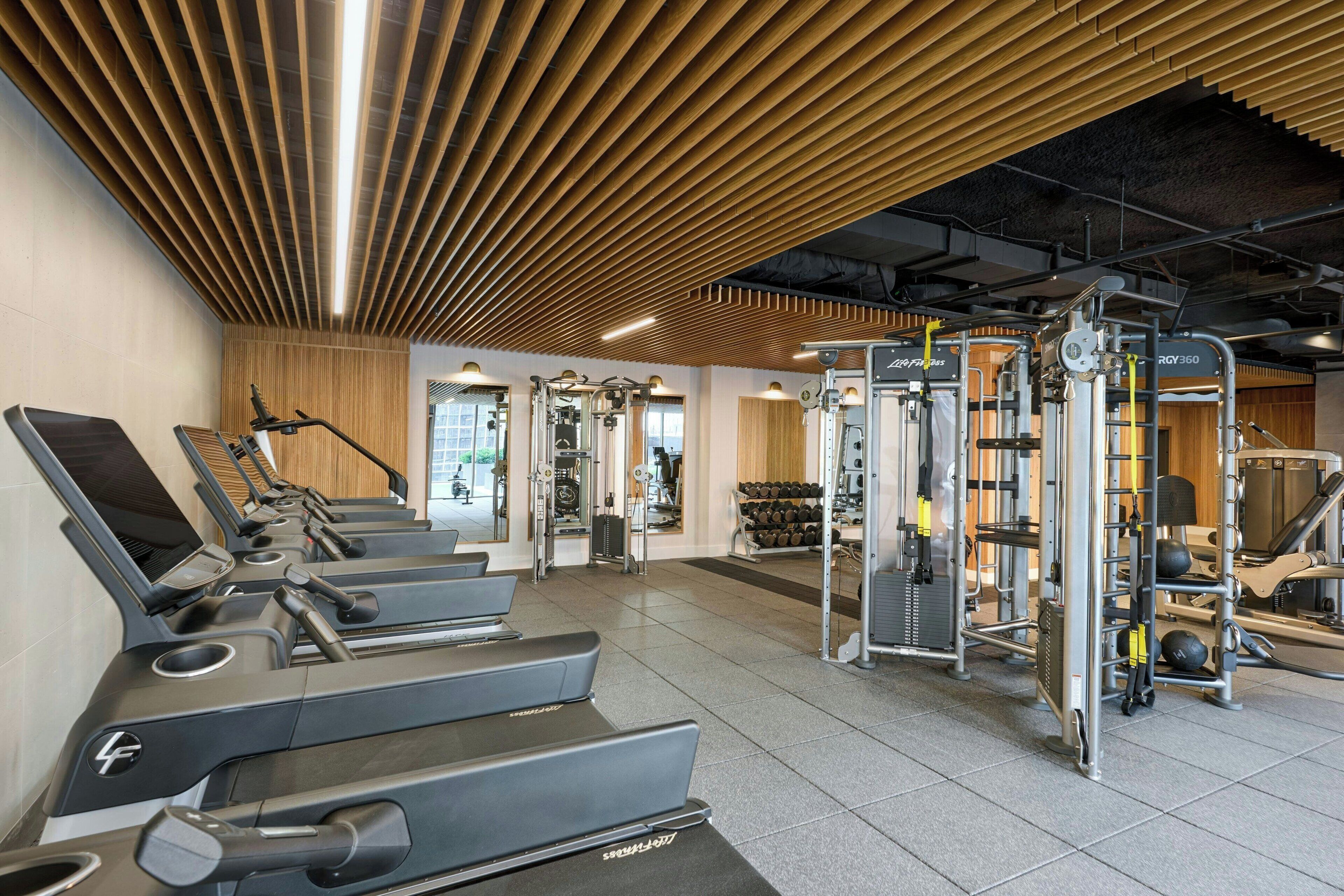 Une salle de sport équipée de tapis de course, d’appareils de musculation et d’haltères.