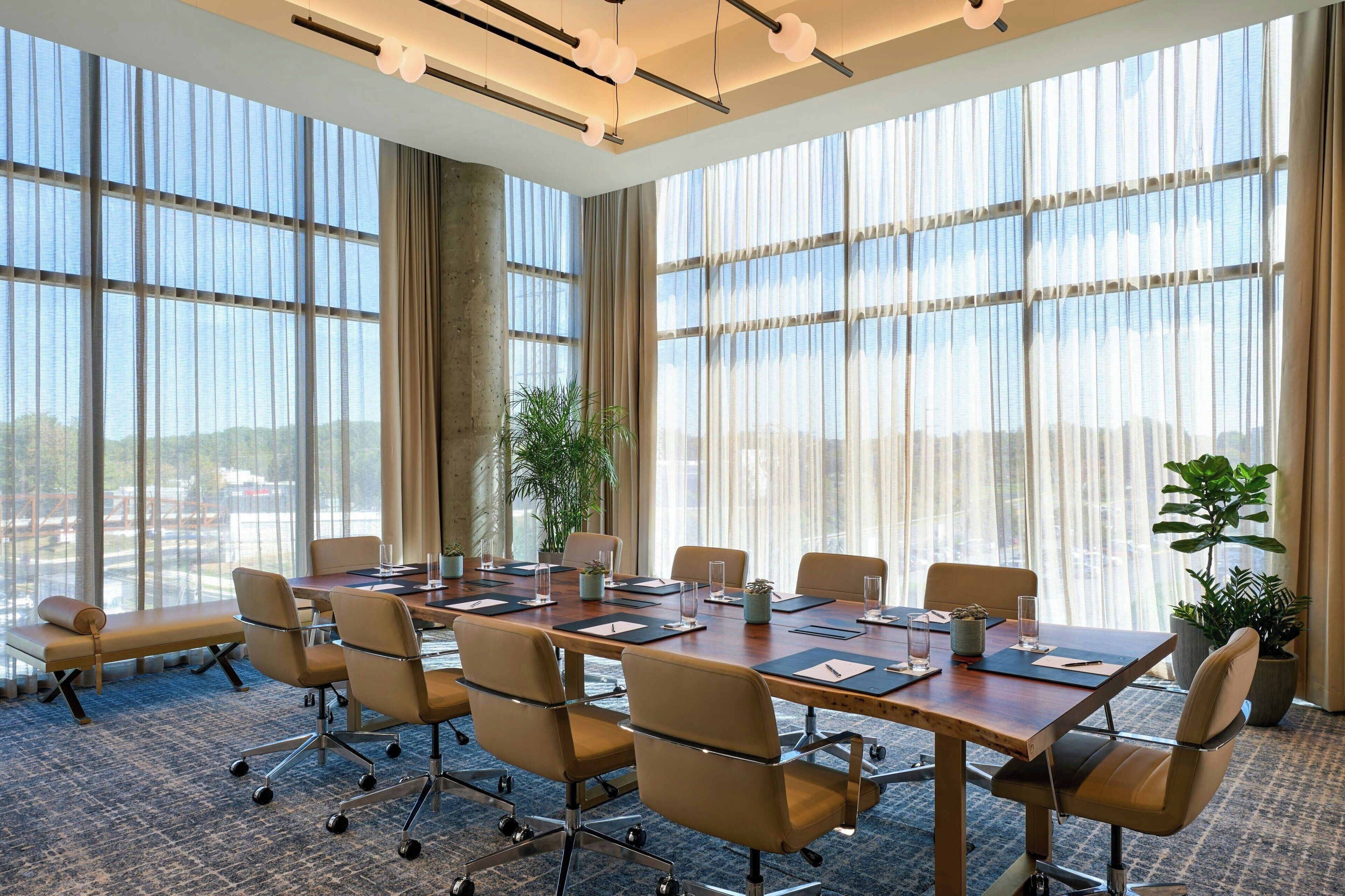 Un salón de conferencias con una gran mesa, sillas y vistas amplias a través de grandes ventanales.