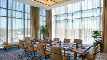 Un salón de conferencias con una gran mesa, sillas y vistas amplias a través de grandes ventanales.