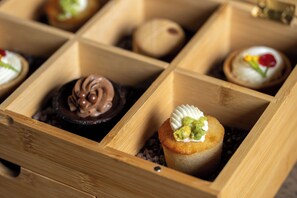 A wooden dessert box with compartments containing various pastries.