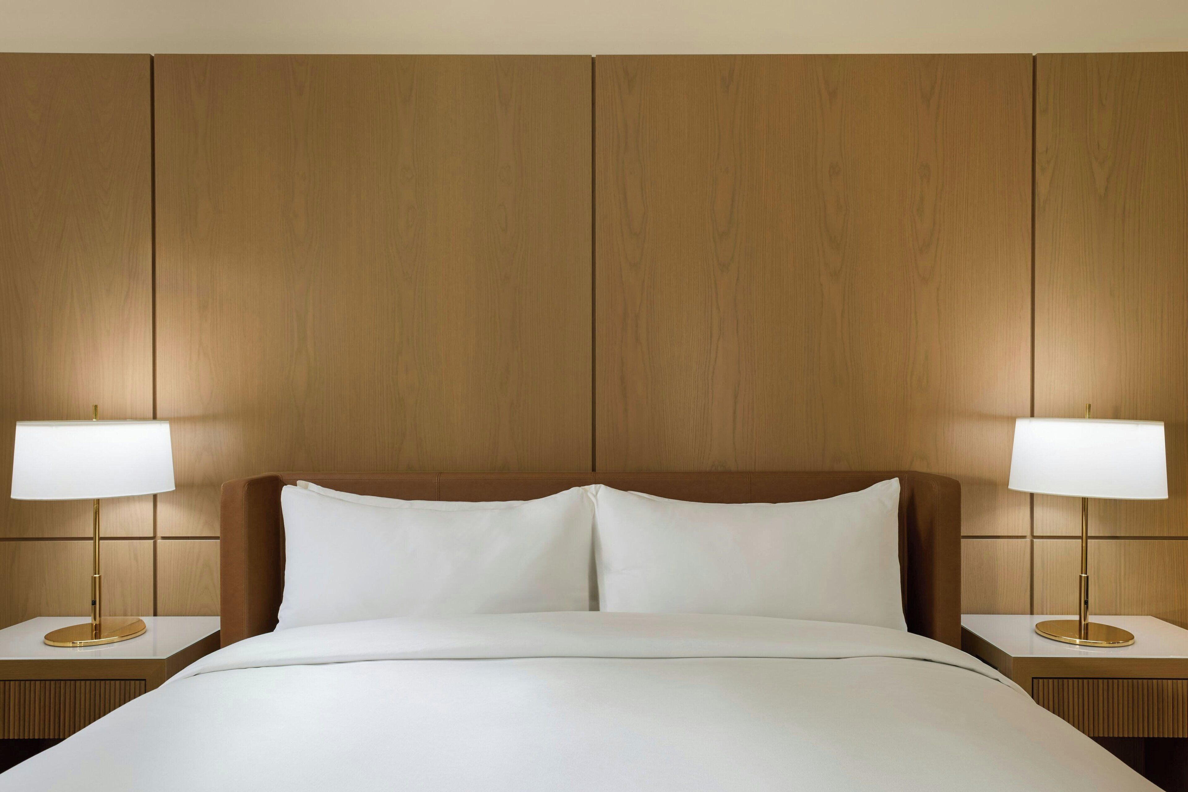 Una habitación de hotel con una cama grande, dos mesitas de noche y un cabecero de madera.