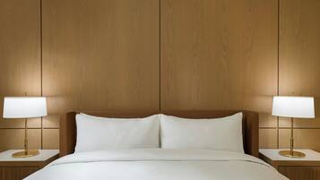 Una habitación de hotel con una cama grande, dos mesitas de noche y un cabecero de madera.