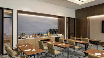 Une salle de conférence équipée d’une longue table, de chaises, d’un coin café et d’un grand écran.