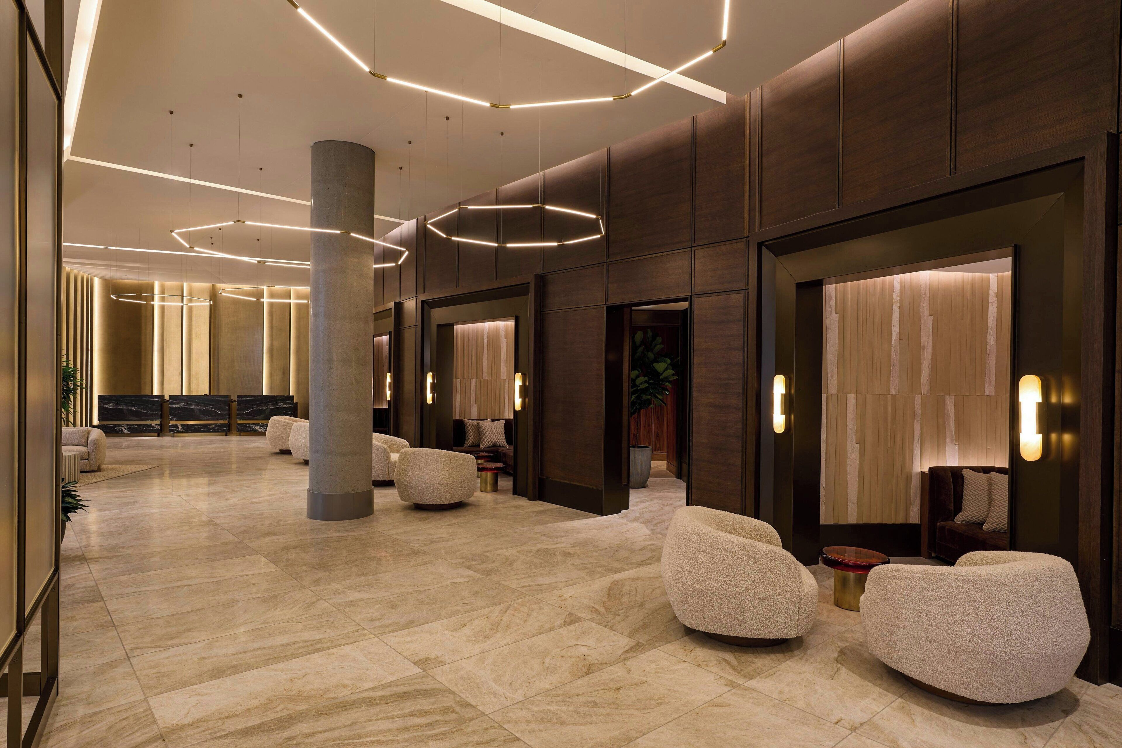 A spacious lobby with a marble floor, modern seating, and ambient lighting.