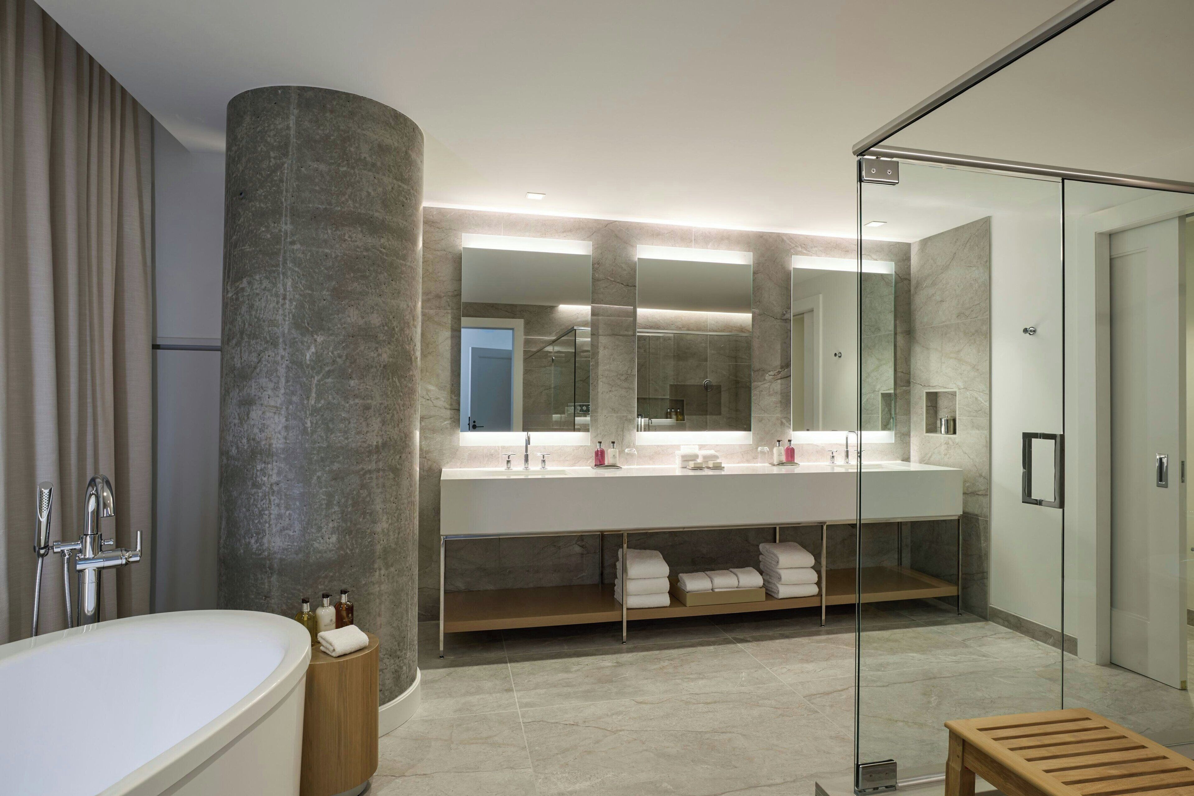 A modern bathroom with a large bathtub, a double vanity with a mirror, and a glass shower enclosure.
