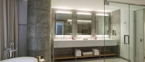 A modern bathroom with a large bathtub, a double vanity with a mirror, and a glass shower enclosure.