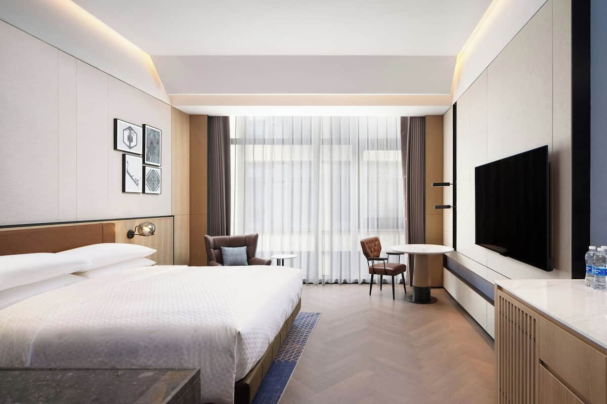 Een hotelkamer met een bed, een televisie, een bureau en een stoel.