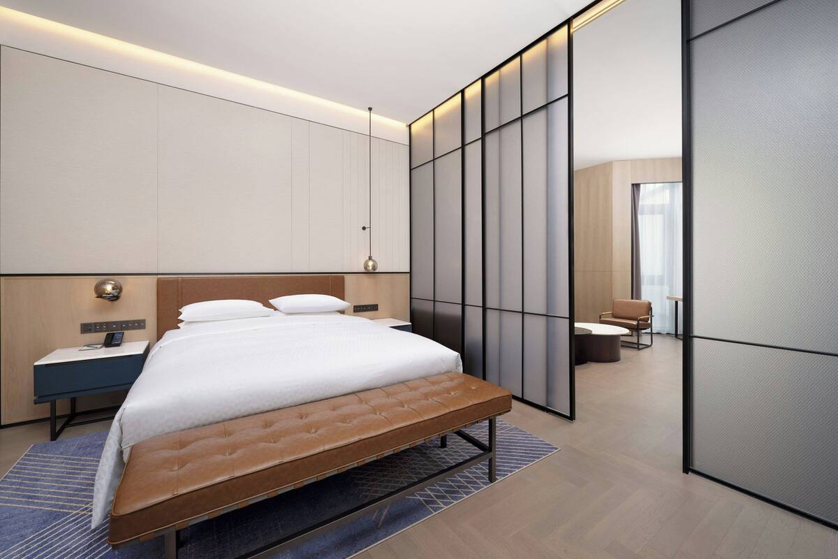 Een moderne hotelkamer met een groot bed, nachtkastjes, een bureau en een zithoek.