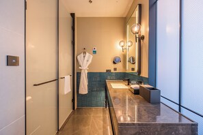 Une salle de bain moderne dotée d’une douche à parois de verre, d’un meuble-lavabo en marbre, d’un porte-serviettes et d’un grand miroir agrémenté d’appliques murales.