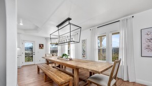 Een ruime eetruimte met een lange houten tafel, banken en een moderne hanglamp.