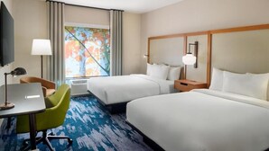 Habitación de hotel con dos camas, un escritorio con silla, televisor y ventana con cortinas.