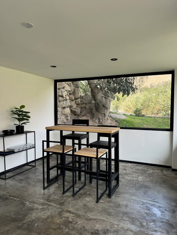 A modern room with a large window, a stone wall, and a minimalist table and chairs arrangement. - Casa San Lorenzo by Wynwood House (Santa Eulalia)
