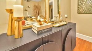 A dark wood vanity with gold accents, a mirror, and a book titled "Da Vinci: The Fashion House". - NEW! Upscale Private 3 Bed, Free Parking, W&D, Near MBTA, Backyard (Boston)