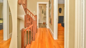 A hallway with wooden flooring, a wooden staircase, and a door leading to another room. - NEW! Upscale Private 3 Bed, Free Parking, W&D, Near MBTA, Backyard (Boston)