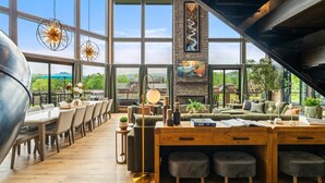 Un restaurant spacieux avec de hauts plafonds, de grandes fenêtres et un coin salon confortable.