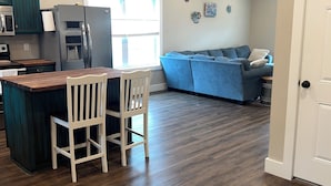 Una cocina moderna con comedor, un sofá azul y suelo de madera.