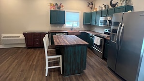 Una cocina moderna con armarios verde mar, una isla de madera y electrodomésticos de acero inoxidable.