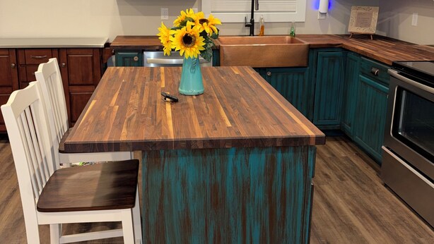 Una cocina con armarios color turquesa, una isla de madera, un lavabo y una estufa.