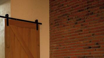 A bedroom with a wooden bed, a red and white bedspread, and a brick wall.